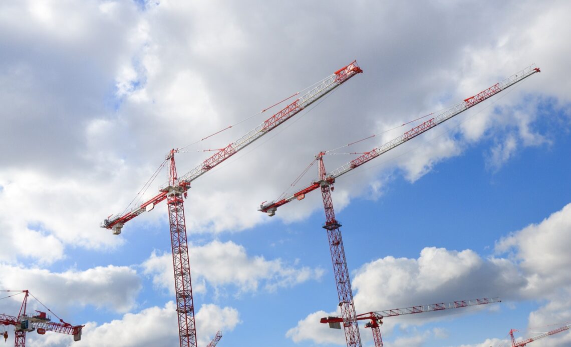 Ensemble de grues sur un chantier de bâtiment, dans le ciel bleu